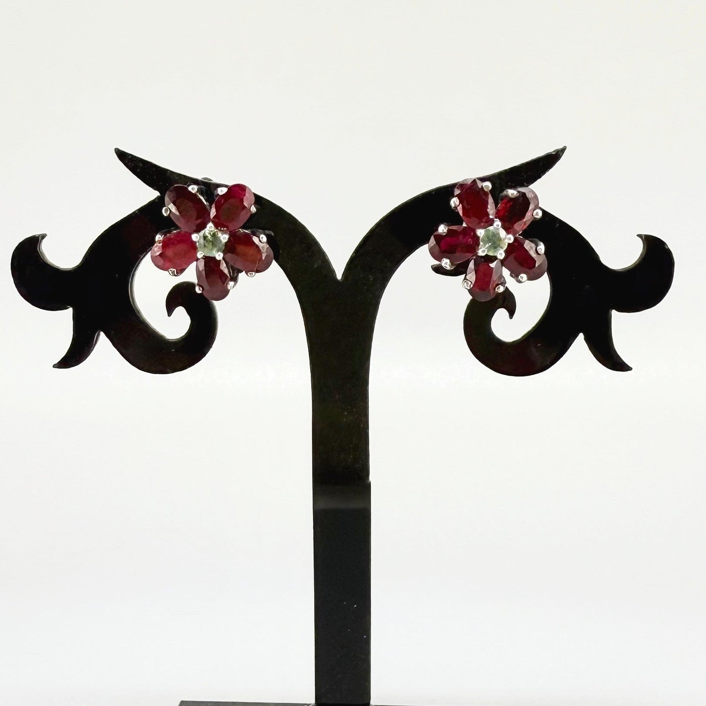 White gold plated silver floral earrings with 5.85 ct rubies and 0.32 ct sapphires; elegant red and blue gemstone flower design.