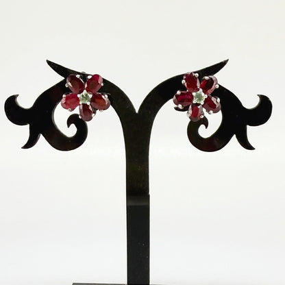 White gold plated silver floral earrings with 5.85 ct rubies and 0.32 ct sapphires; elegant red and blue gemstone flower design.