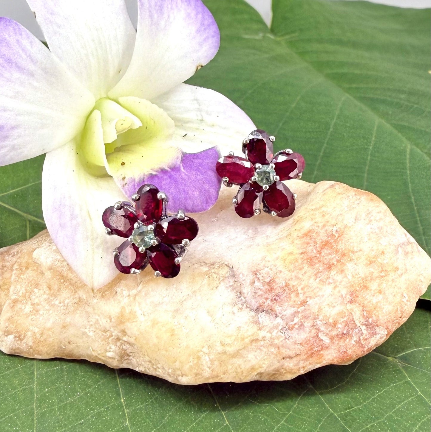 White gold plated silver floral earrings with 5.85 ct rubies and 0.32 ct sapphires; elegant red and blue gemstone flower design.