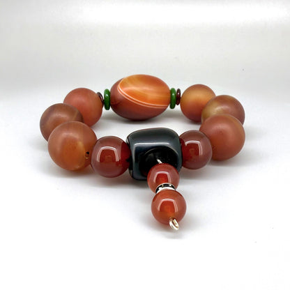 Carnelian and agate beaded bracelet, 20cm, red-orange gemstone beads with large black square bead on elastic stretch band.