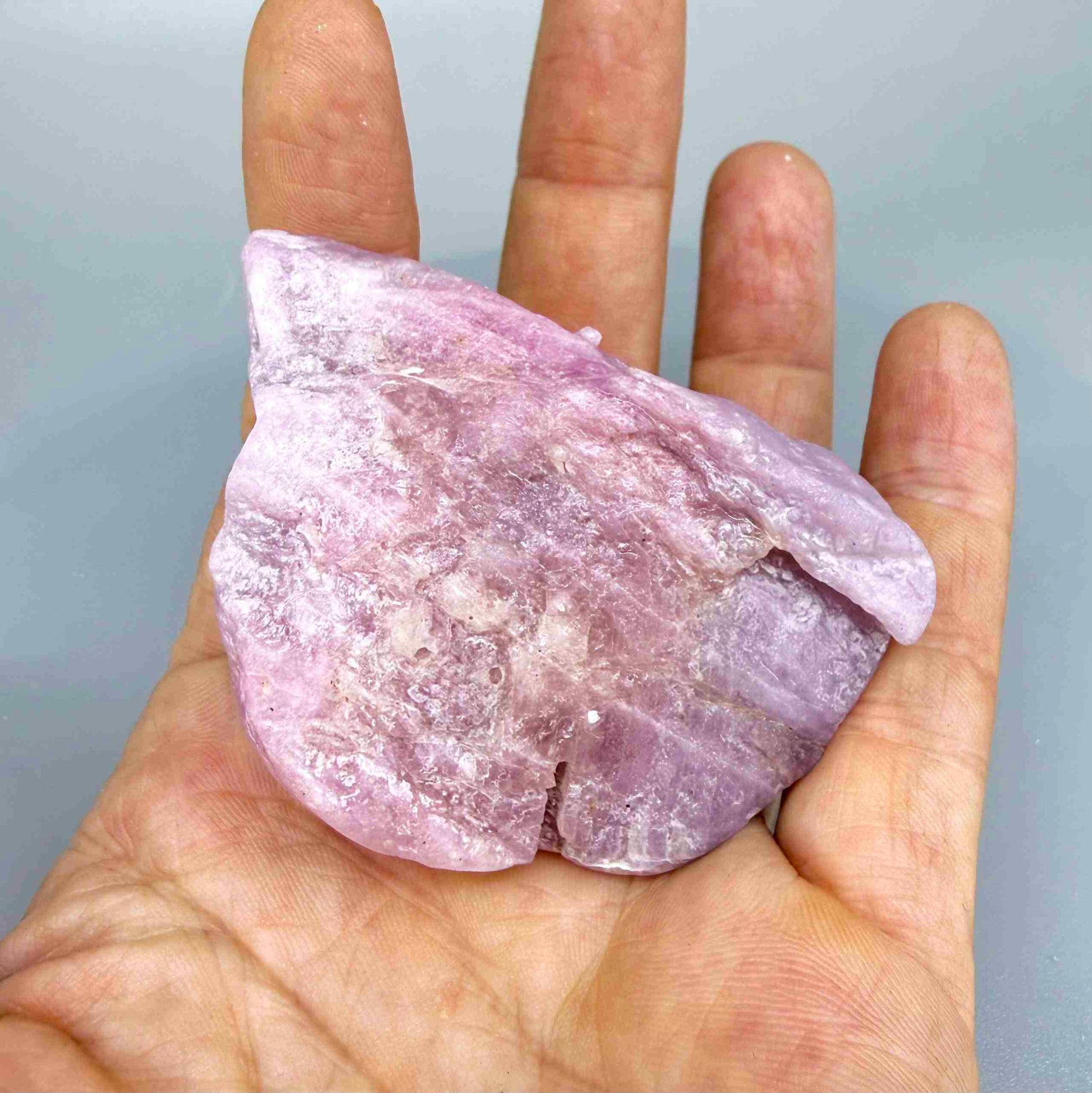 Natural ruby rough stone in soft pink to pale rose tones, uncut corundum specimen photographed on neutral background.