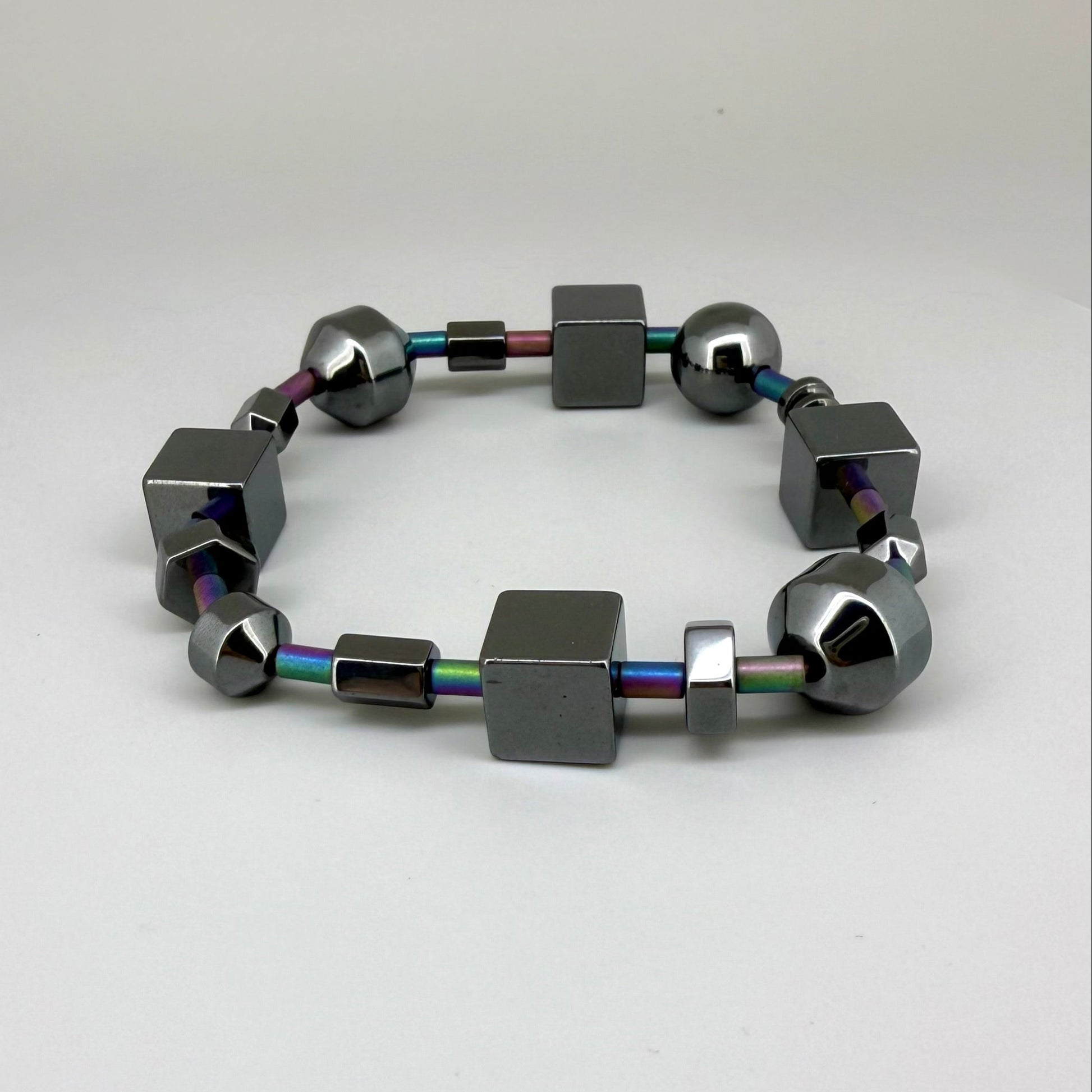 Hematite bracelet, 20cm, geometric cube and sphere beads with rainbow-toned connectors on elastic stretch band.