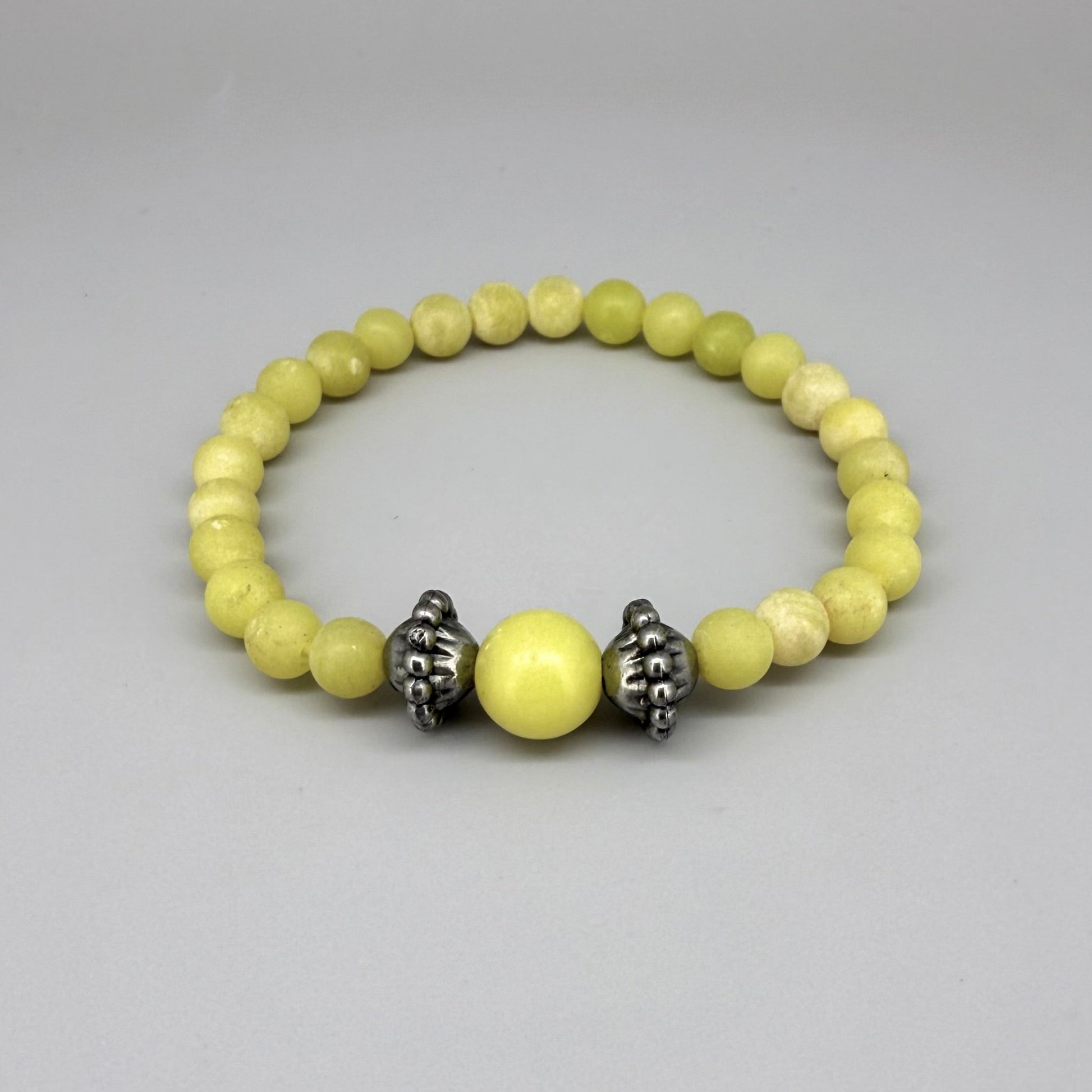 Yellow jasper beaded bracelet, 18cm, vibrant gemstone beads with larger focal bead framed by carved metal accents on elastic stretch band.