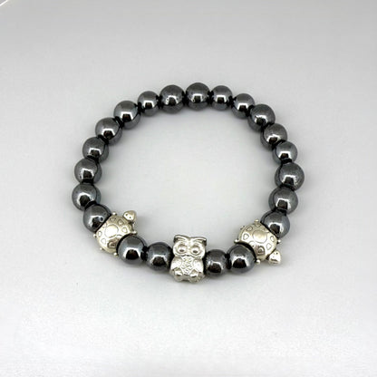 Hematite beaded bracelet, 18cm, metallic dark grey gemstone beads with two turtle accents and one owl charm on elastic stretch band.