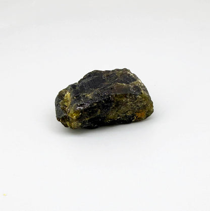 Natural yellow sapphire rough stone with golden orange tones, untreated corundum photographed on neutral background.