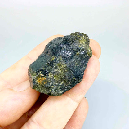 Natural yellow sapphire rough stone with golden orange tones, untreated corundum photographed on neutral background.