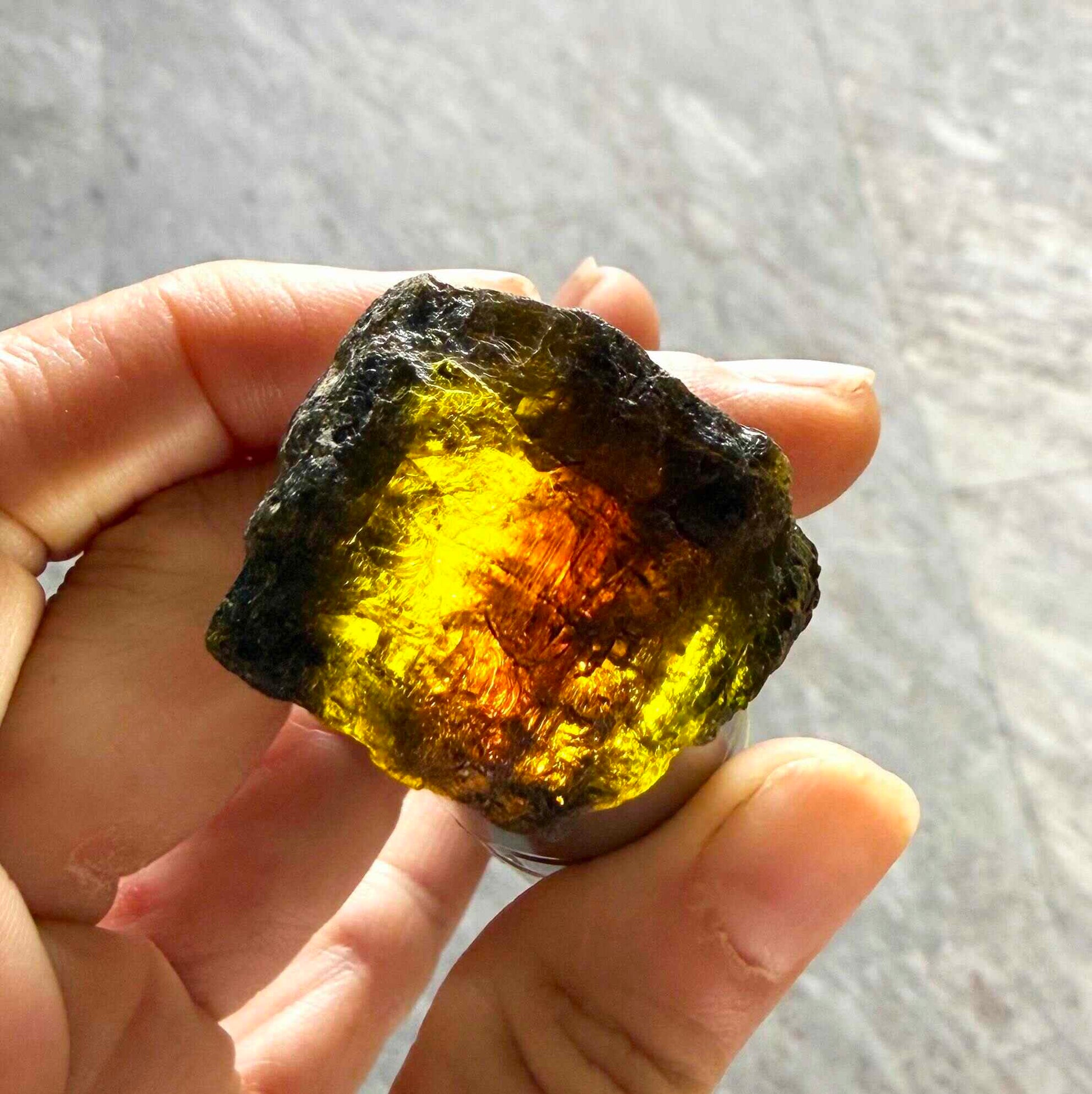 Natural yellow sapphire rough stone with golden orange tones, untreated corundum photographed on neutral background.
