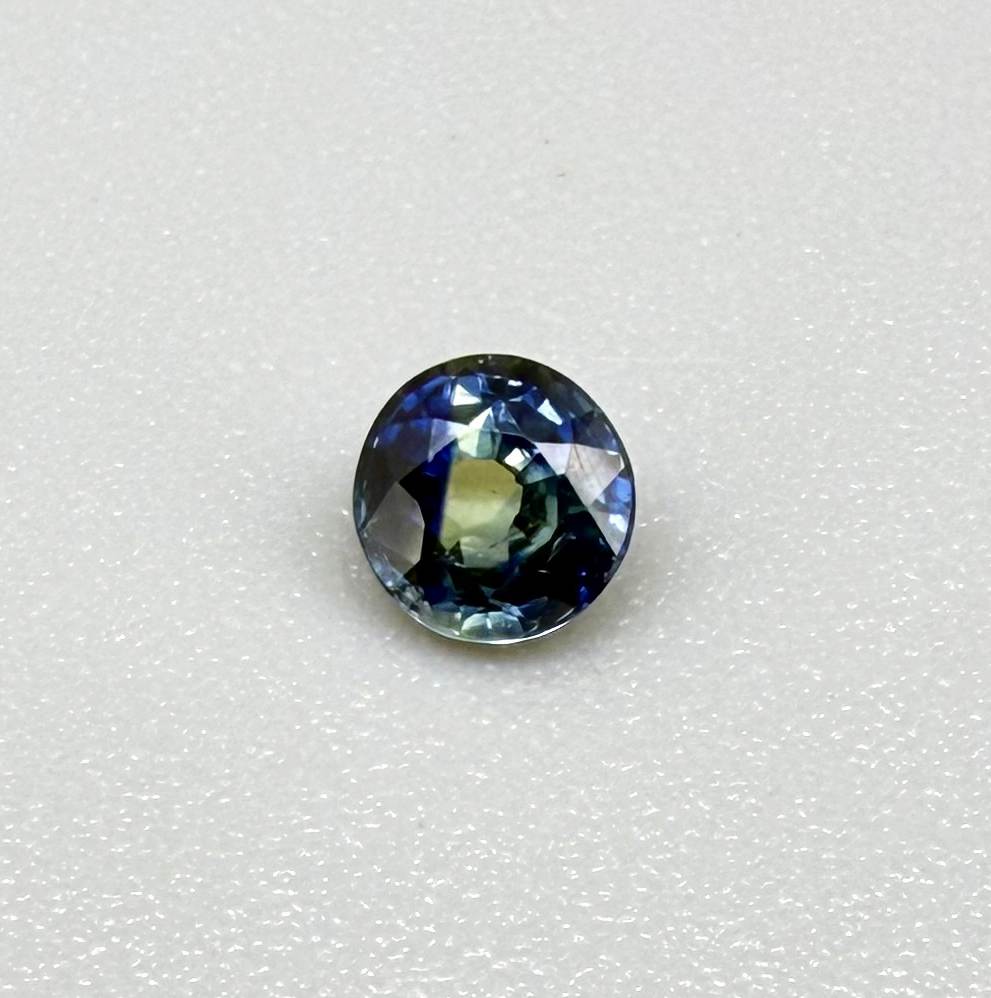 Round-cut bright blue sapphire from Bangkaja, Thailand showing subtle yellow undertone and natural color zoning.