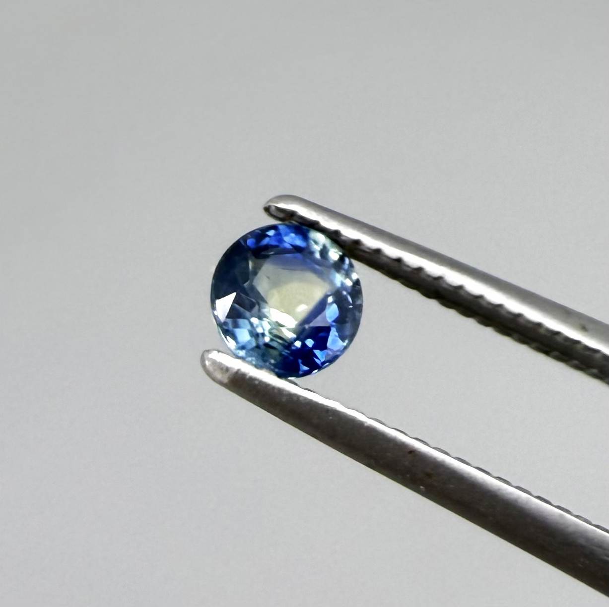 Round-cut bright blue sapphire from Bangkaja, Thailand showing subtle yellow undertone and natural color zoning.