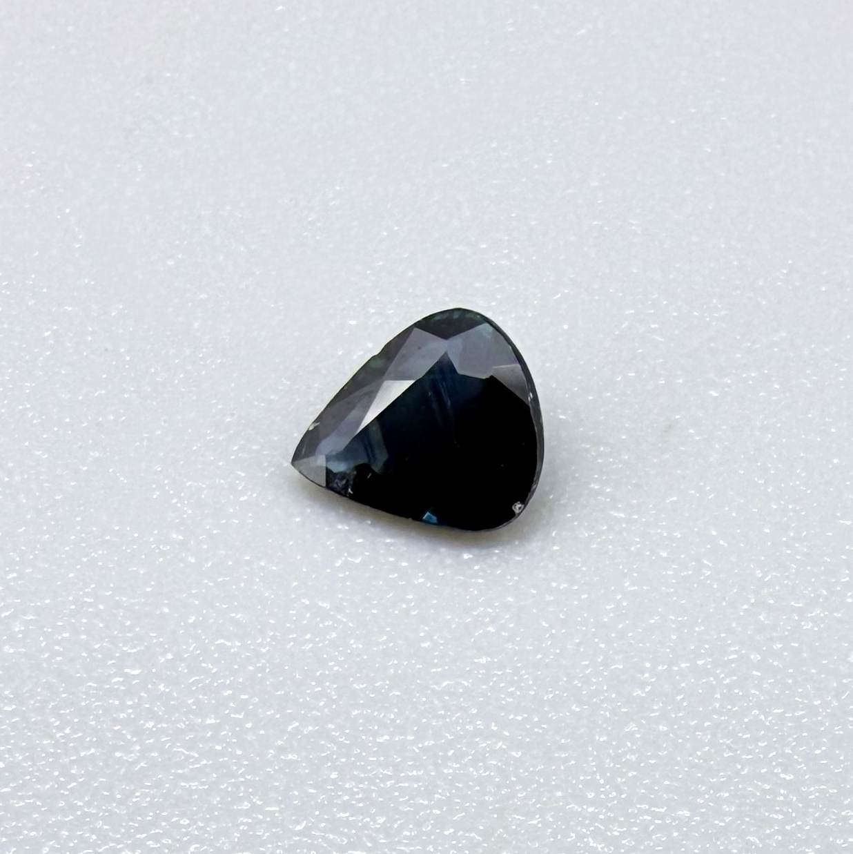 Trillion-cut dark teal blue sapphire from Bangkaja, Thailand, natural faceted gemstone with deep blue-green undertones.