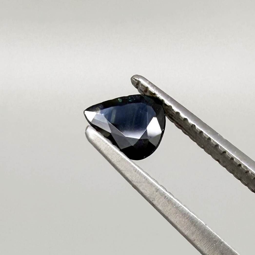 Trillion-cut dark teal blue sapphire from Bangkaja, Thailand, natural faceted gemstone with deep blue-green undertones.