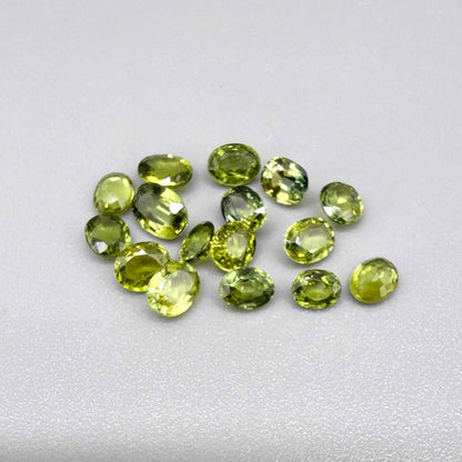 Small parcel of lime green sapphires from Bangkaja, Thailand in oval mixed cuts, natural faceted gemstones.