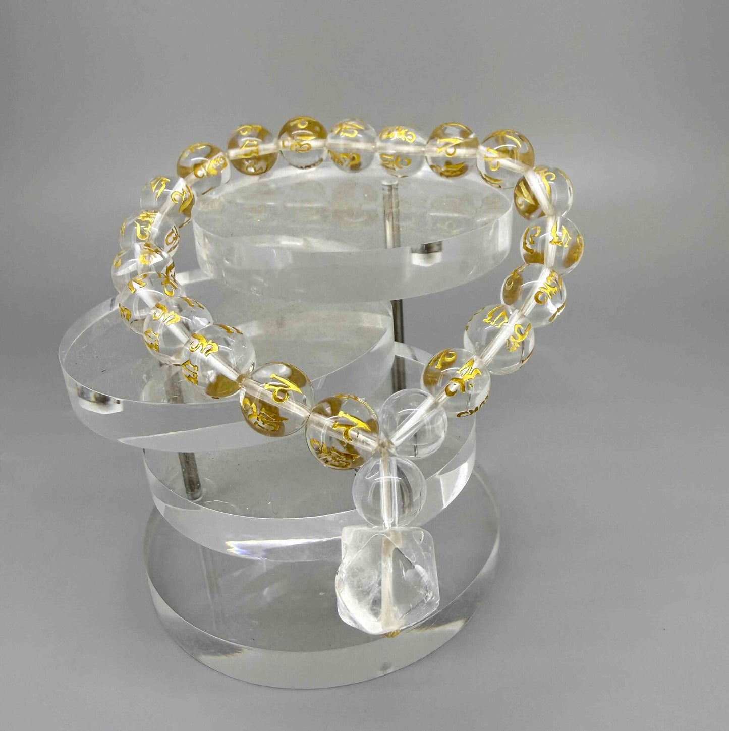 Clear quartz mala bracelet with 21 engraved beads featuring golden Om Mani Padme Hum mantra on elastic cord