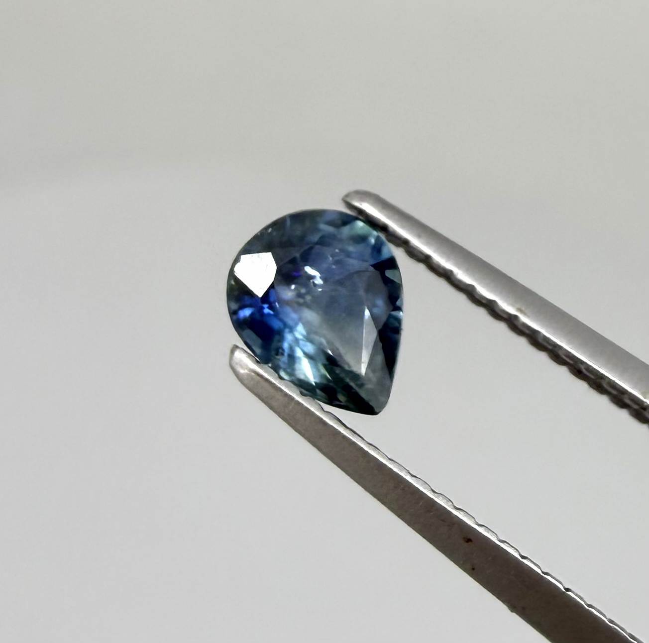 Pear teal blue sapphire from Bangkaja, Thailand with blue-green tones and natural color zoning.