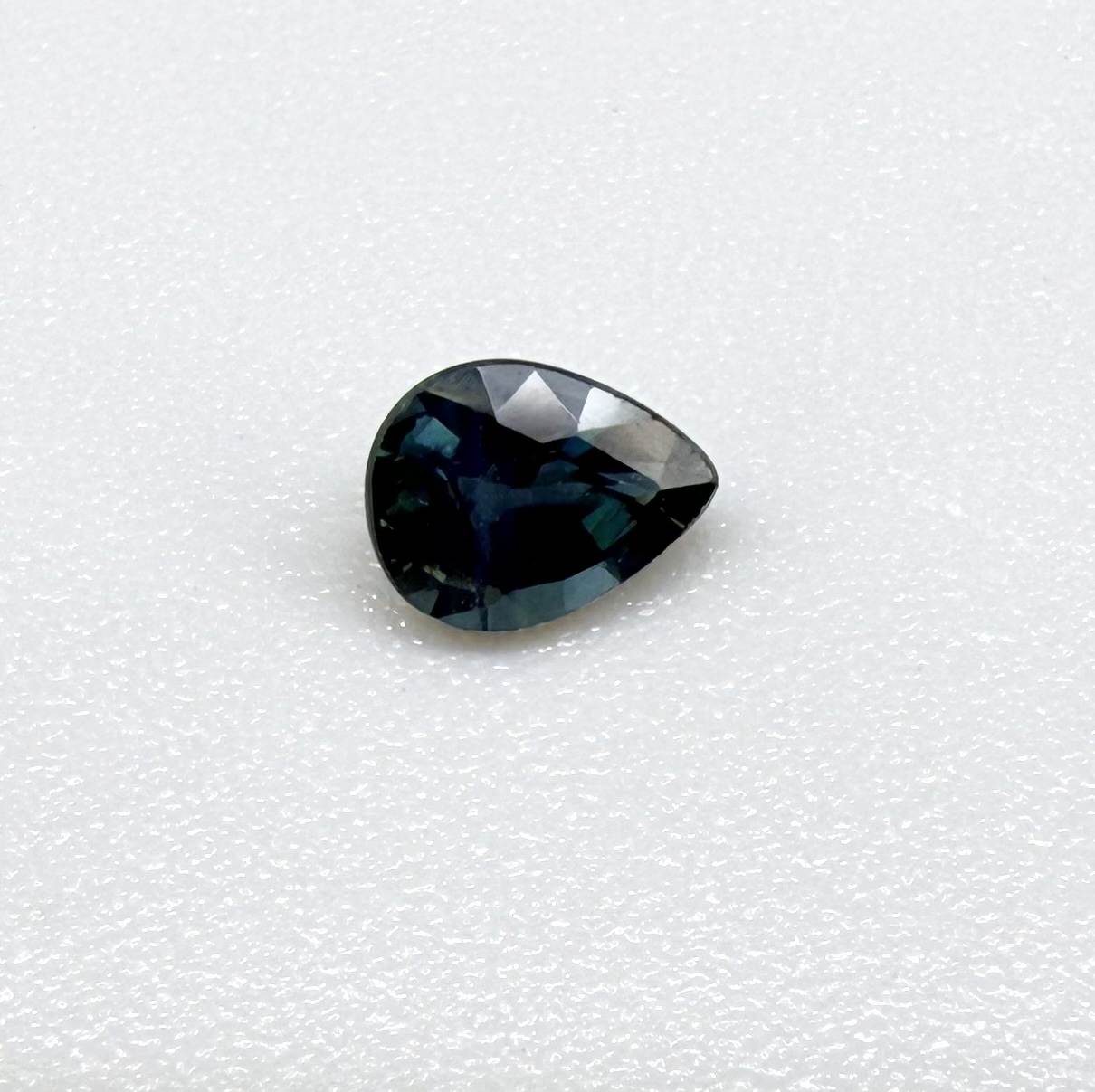 Dark teal blue sapphire from Bangkaja, Thailand in pear cut with deep tone and subtle greenish blue undertone.