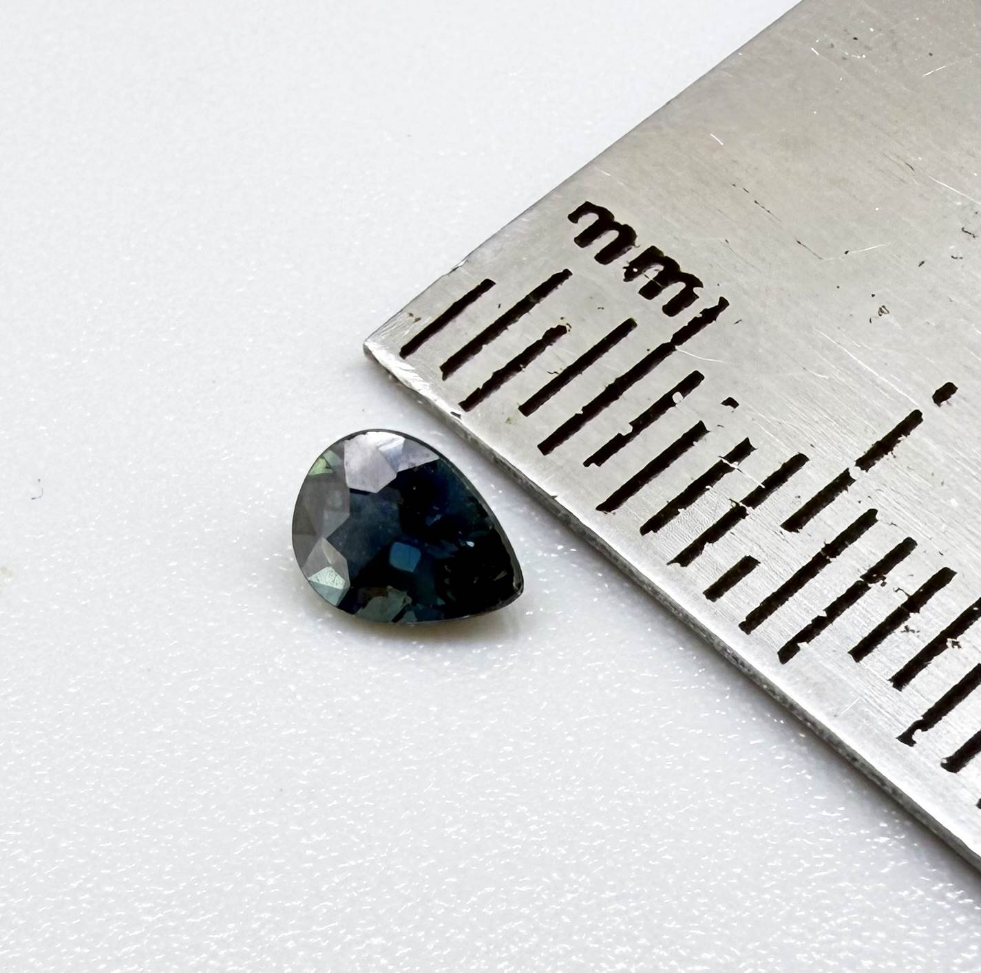 Dark teal blue sapphire from Bangkaja, Thailand in pear cut with deep tone and subtle greenish blue undertone.