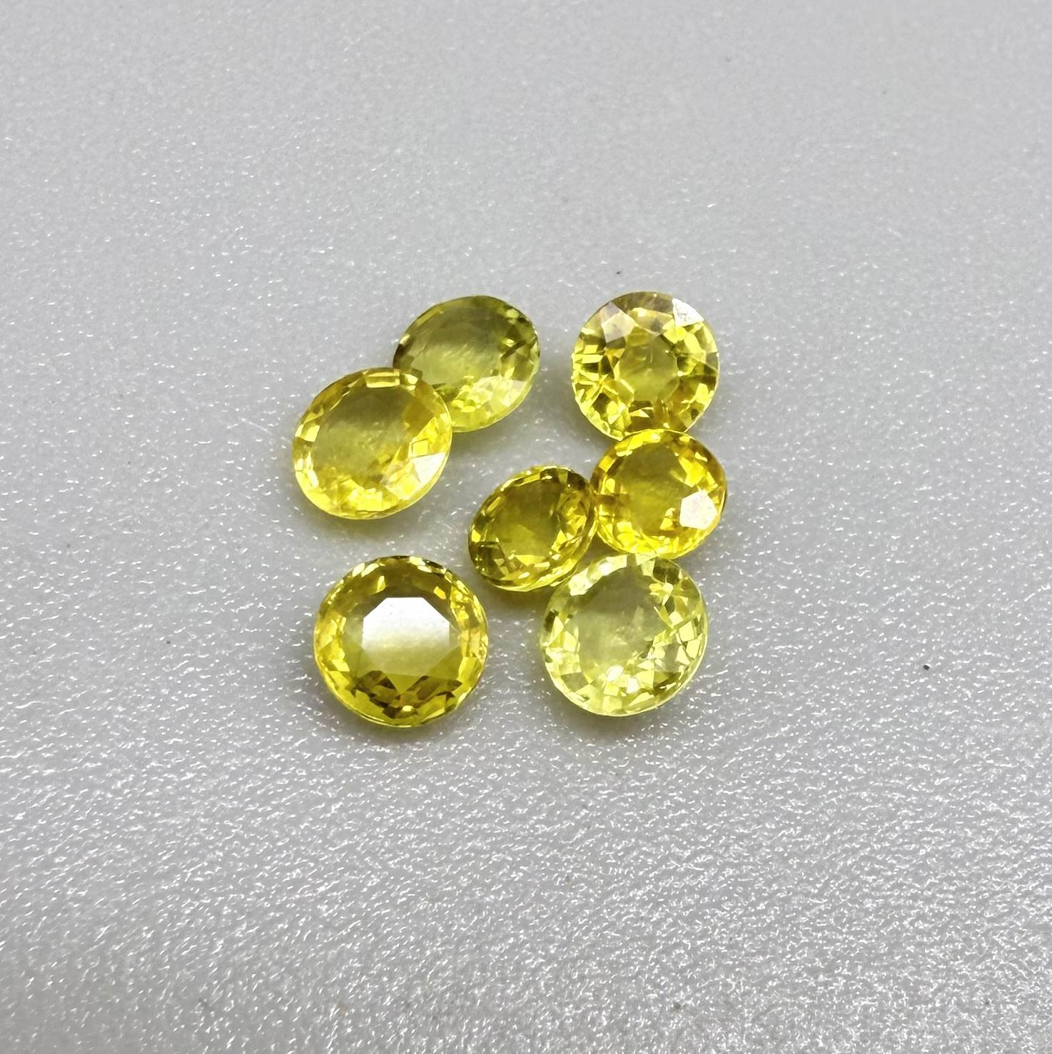 Yellow sapphire parcel in oval and round cuts from Bangkaja, Thailand showing lemon to light golden tones with bright natural brilliance.
