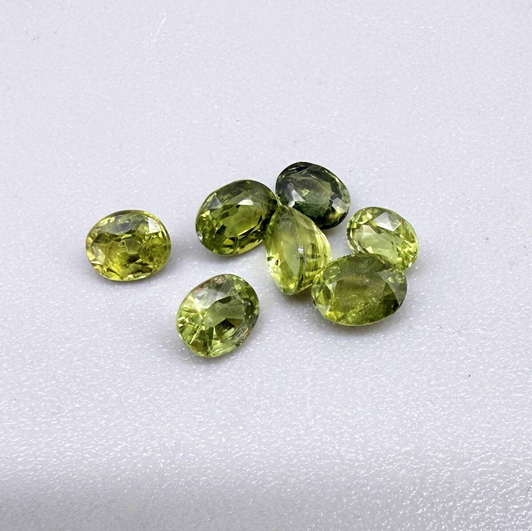 Green sapphire parcel in oval cuts from Bangkaja, Thailand showing yellowish-green to olive tones with natural brilliance.