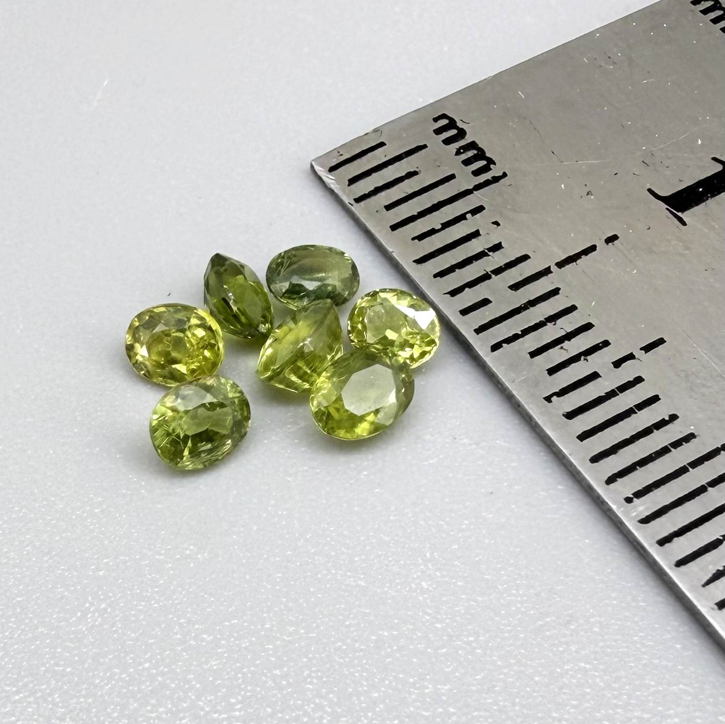 Green sapphire parcel in oval cuts from Bangkaja, Thailand showing yellowish-green to olive tones with natural brilliance.