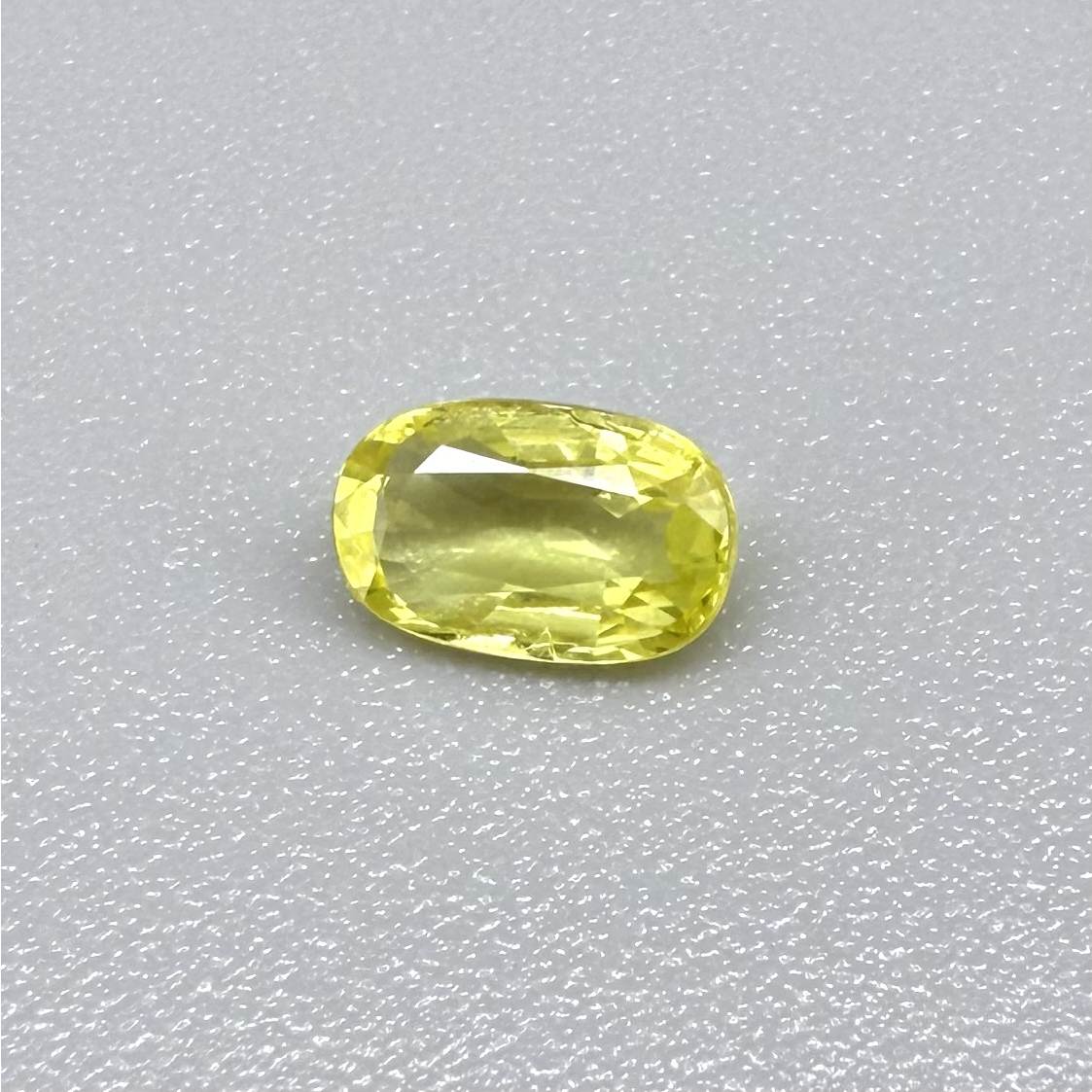 Cushion-cut lemon yellow sapphire from Bangkaja, Thailand with soft bright color and natural brilliance.