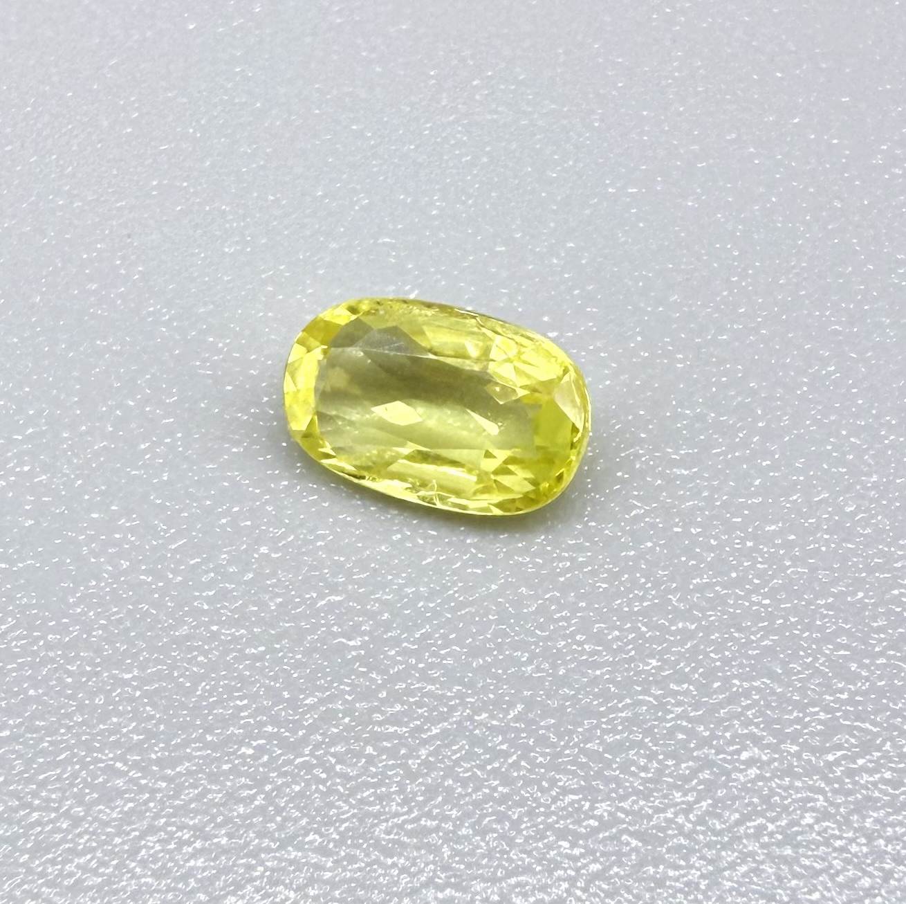 Cushion-cut lemon yellow sapphire from Bangkaja, Thailand with soft bright color and natural brilliance.
