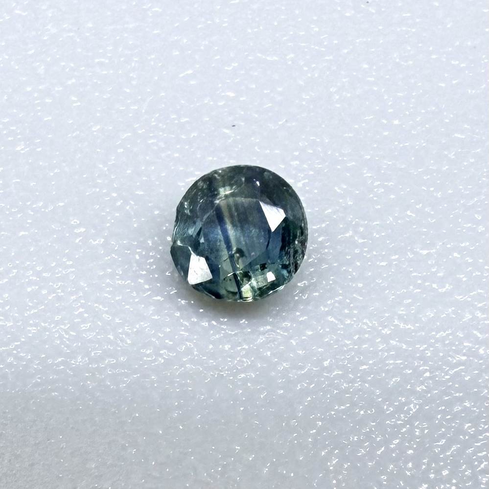 Round petrol blue sapphire from Bangkaja, Thailand with deep blue-green tone and natural color zoning.