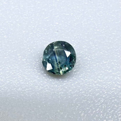 Round petrol blue sapphire from Bangkaja, Thailand with deep blue-green tone and natural color zoning.