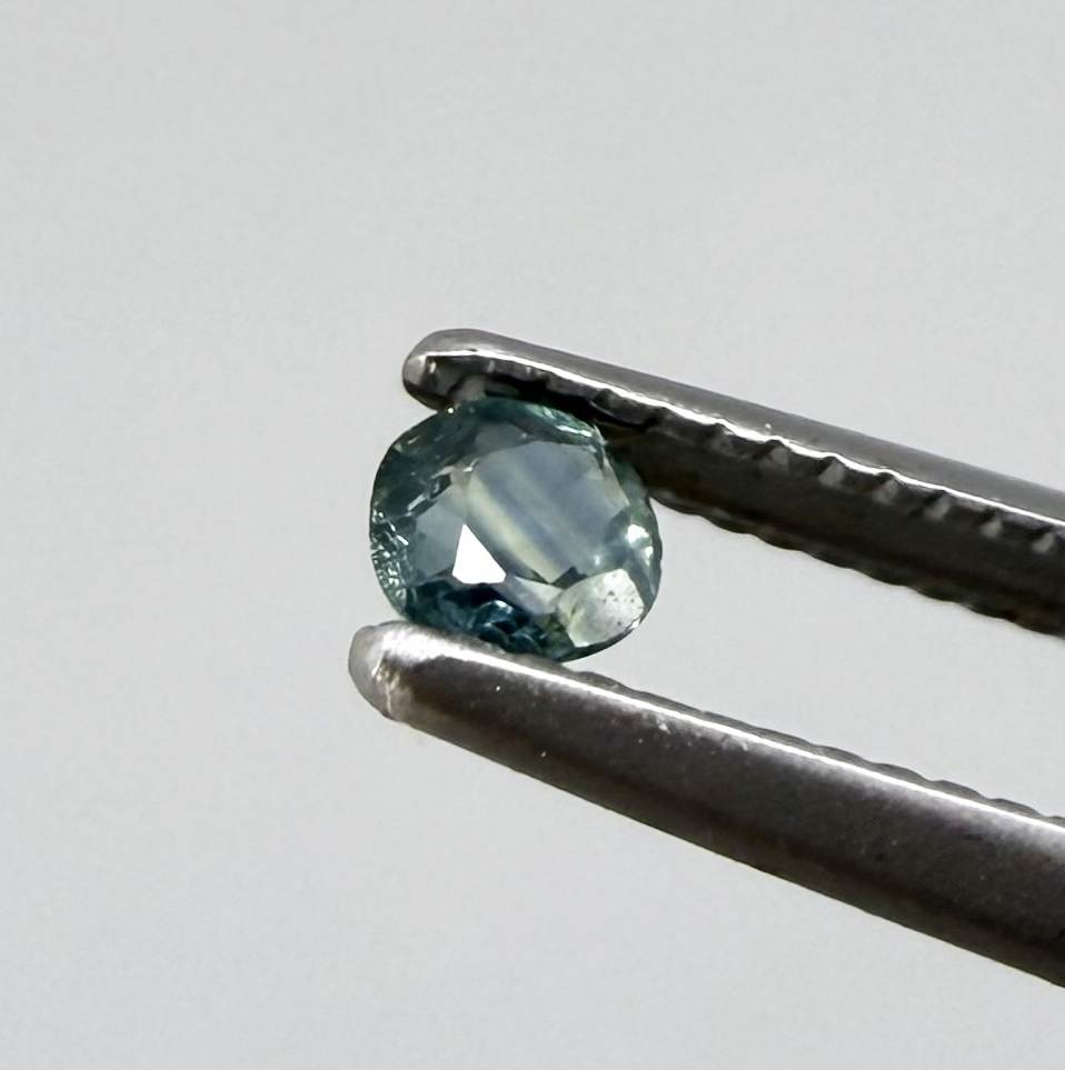 Round petrol blue sapphire from Bangkaja, Thailand with deep blue-green tone and natural color zoning.