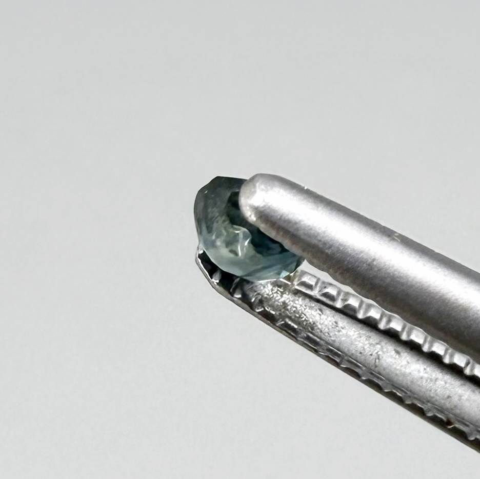 Round petrol blue sapphire from Bangkaja, Thailand with deep blue-green tone and natural color zoning.