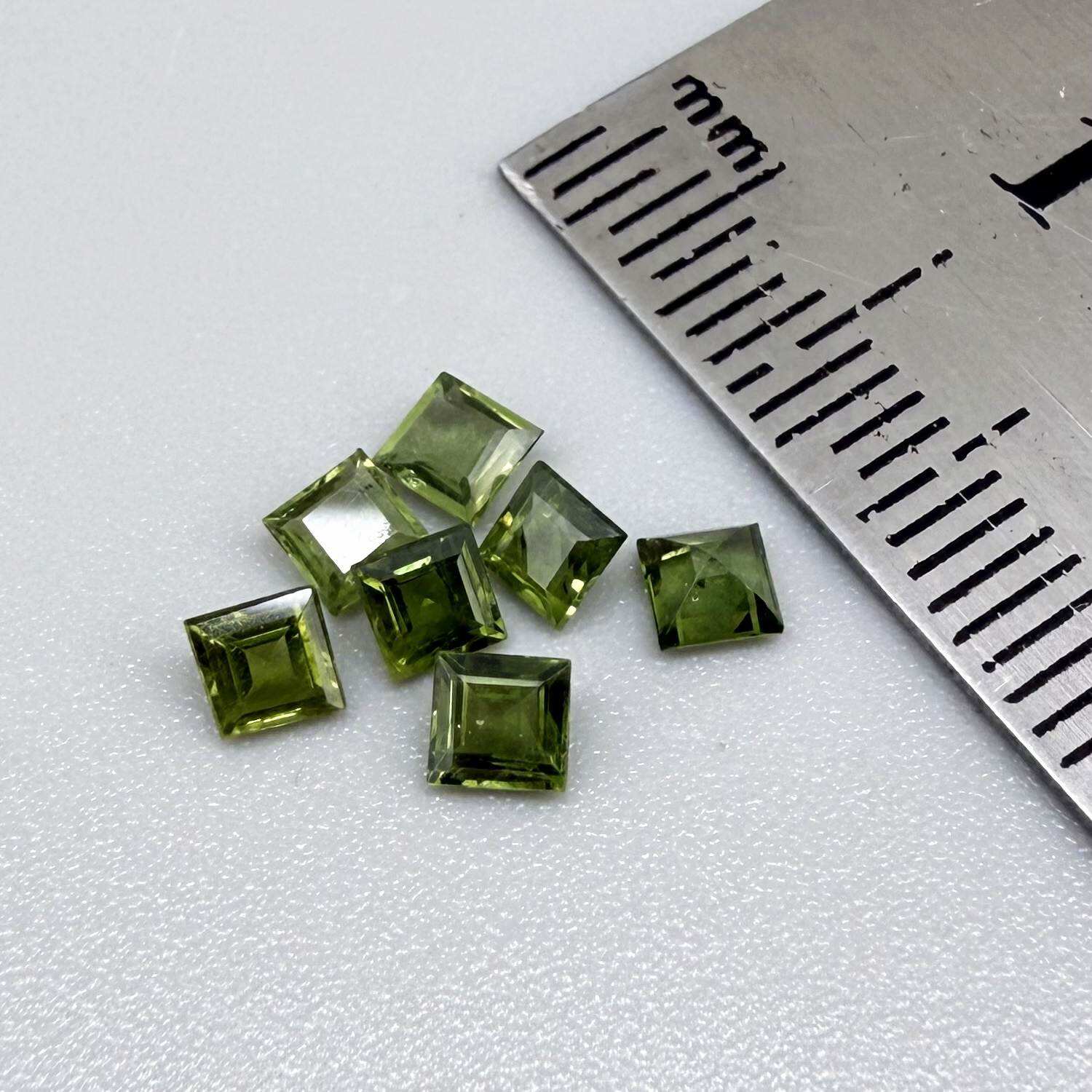 Green sapphire parcel in square cuts from Bangkaja, Thailand showing olive to yellowish-green tones with natural brilliance.