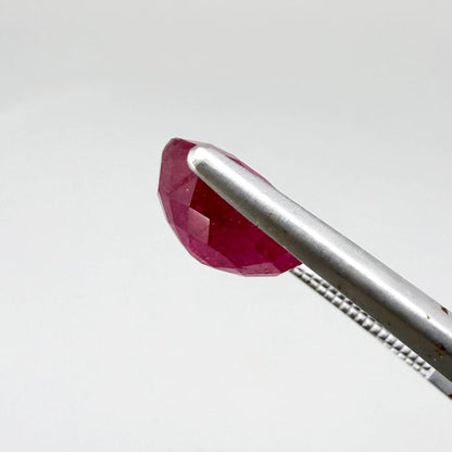 Oval pinkish red ruby from Mozambique with vibrant color, visible natural inclusions and soft, semi-transparent appearance.