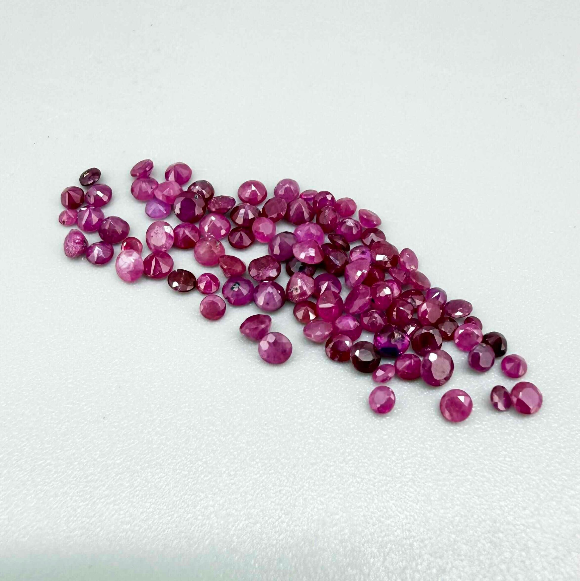 Ruby parcel with mixed pinkish red to reddish pink tones in small faceted cuts, showing natural inclusions and lively brilliance.