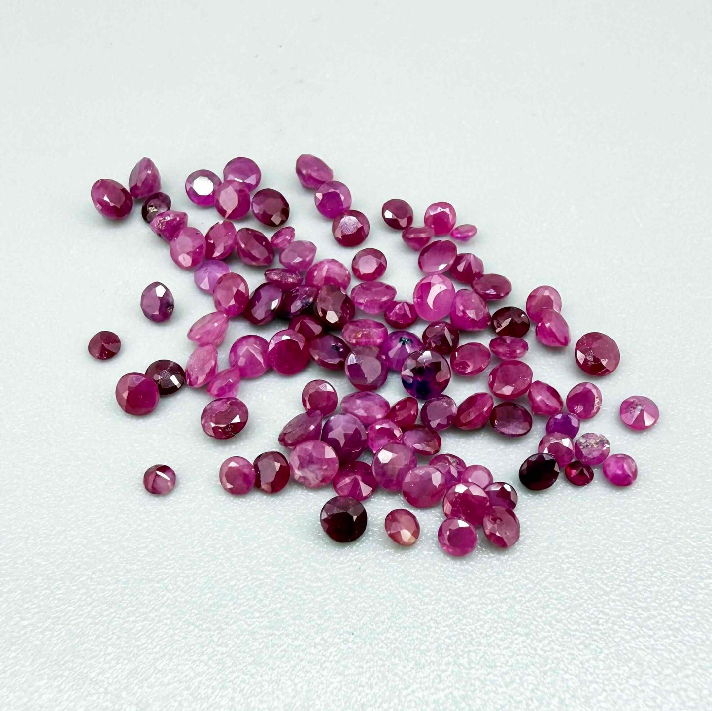 Ruby parcel with mixed pinkish red to reddish pink tones in small faceted cuts, showing natural inclusions and lively brilliance.