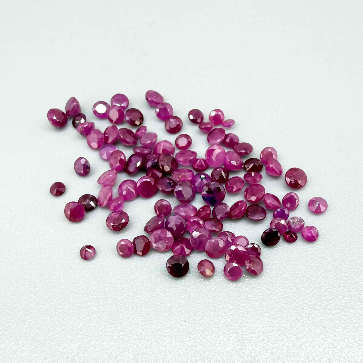 Ruby parcel with mixed pinkish red to reddish pink tones in small faceted cuts, showing natural inclusions and lively brilliance.