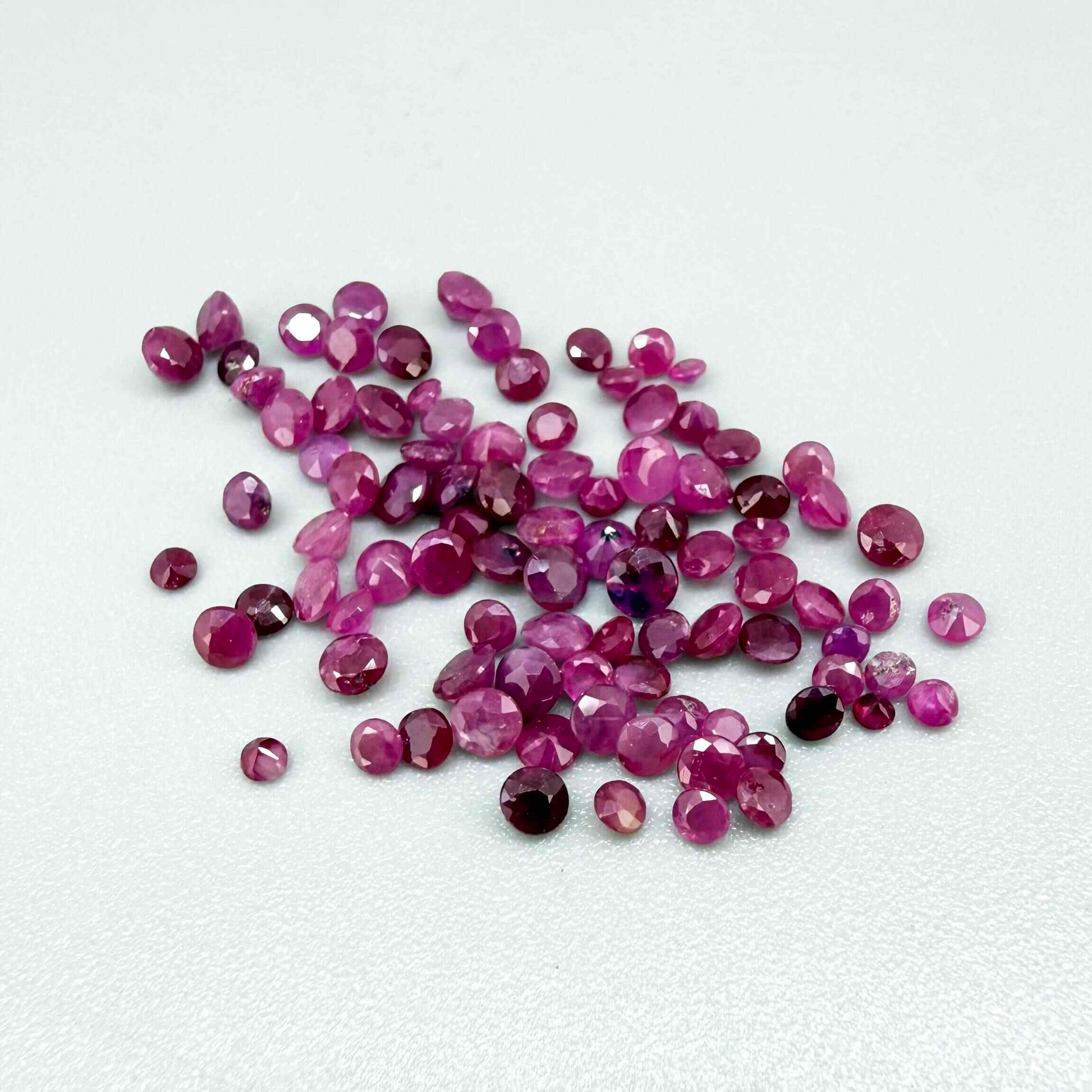 Ruby parcel with mixed pinkish red to reddish pink tones in small faceted cuts, showing natural inclusions and lively brilliance.