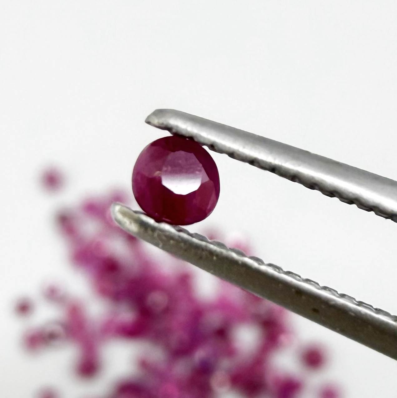 Ruby parcel with mixed pinkish red to reddish pink tones in small faceted cuts, showing natural inclusions and lively brilliance.