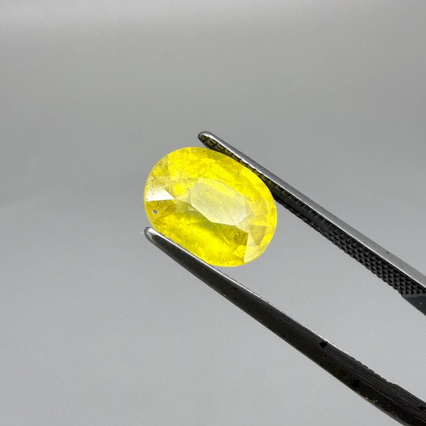 Cushion cut yellow sapphire from Africa,  with vivid golden-yellow color, visible natural inclusions and a transparent to slightly silky structure.