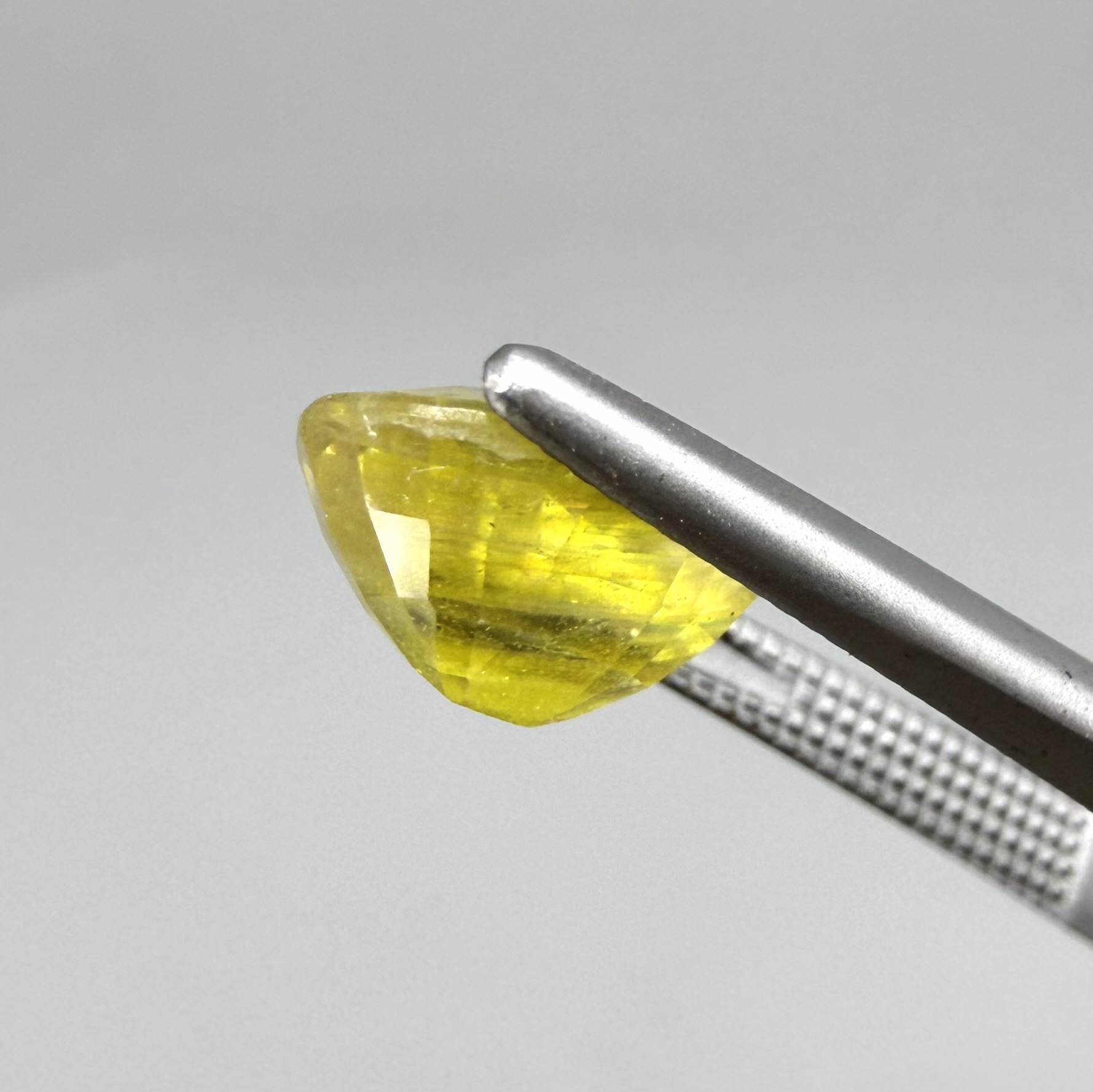 Cushion cut yellow sapphire from Africa,  with vivid golden-yellow color, visible natural inclusions and a transparent to slightly silky structure.