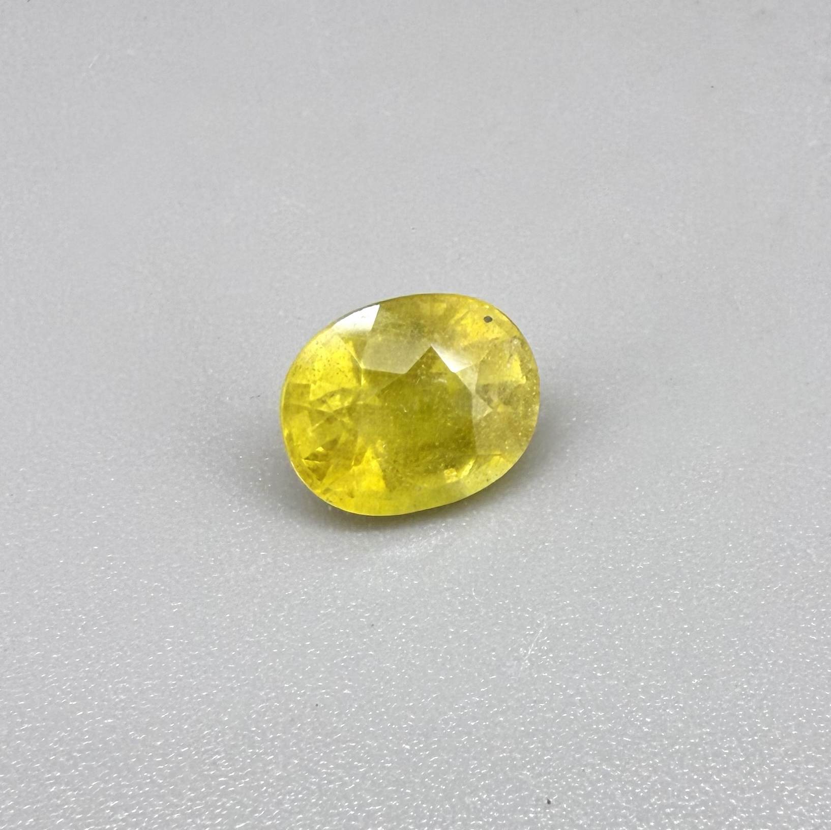 Cushion cut yellow sapphire from Africa,  with vivid golden-yellow color, visible natural inclusions and a transparent to slightly silky structure.