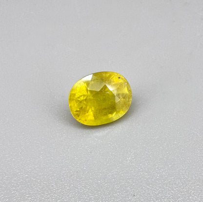 Cushion cut yellow sapphire from Africa,  with vivid golden-yellow color, visible natural inclusions and a transparent to slightly silky structure.
