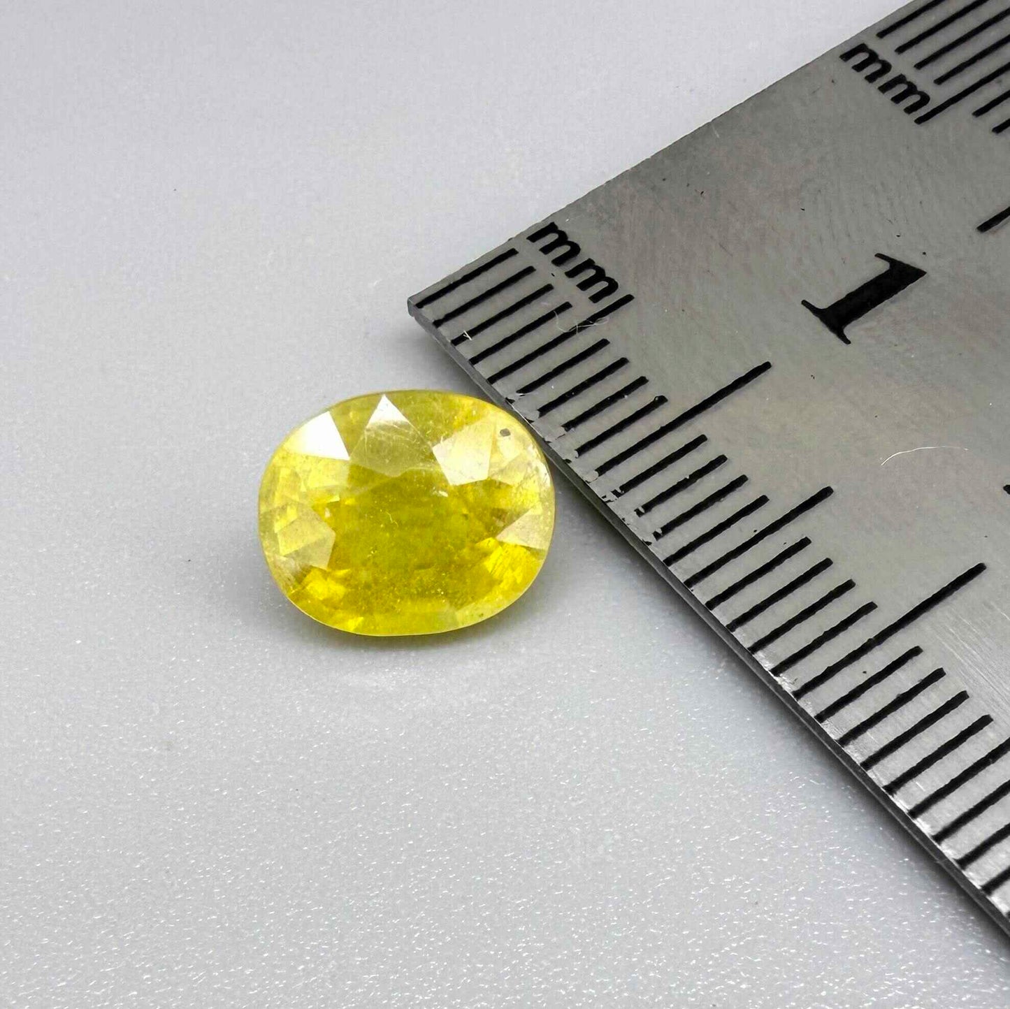 Cushion cut yellow sapphire from Africa,  with vivid golden-yellow color, visible natural inclusions and a transparent to slightly silky structure.