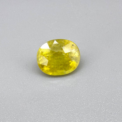 Cushion cut yellow sapphire from Africa,  with vivid golden-yellow color, visible natural inclusions and a transparent to slightly silky structure.