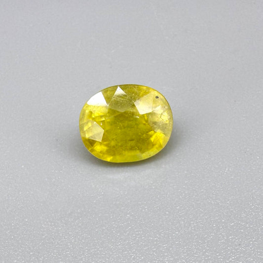 Cushion cut yellow sapphire from Africa,  with vivid golden-yellow color, visible natural inclusions and a transparent to slightly silky structure.