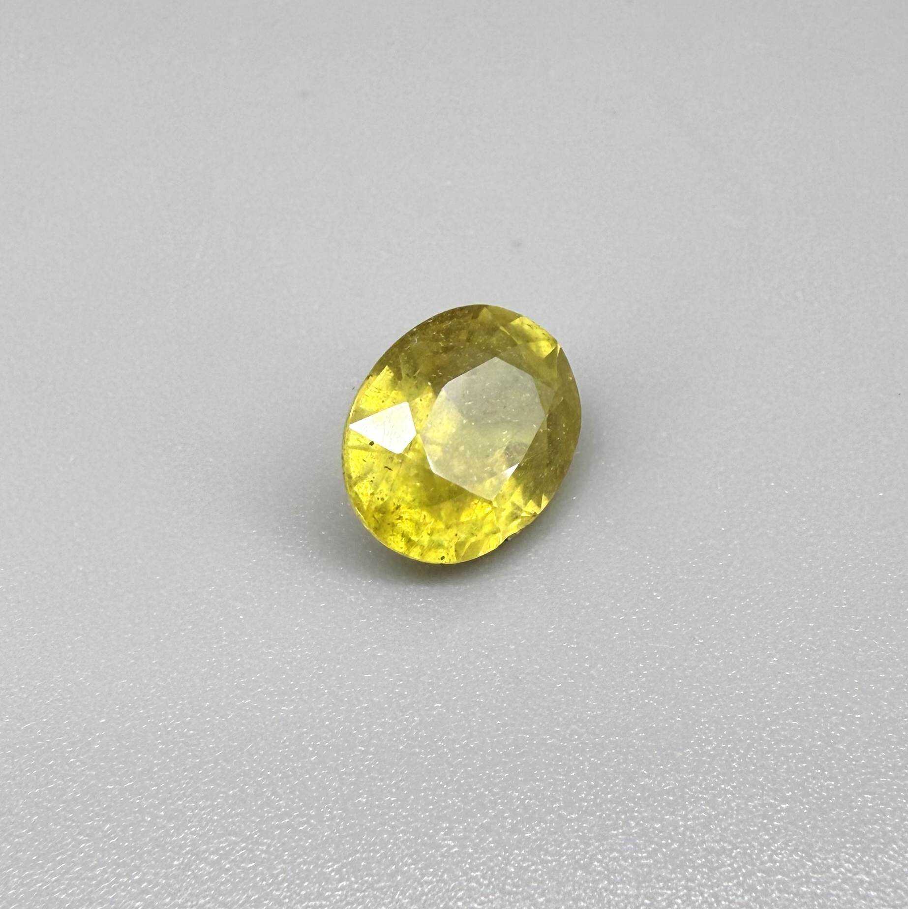 Oval yellow sapphire from Africa, 5.42ct, with vivid golden-yellow color, visible natural inclusions and a transparent to slightly silky appearance.