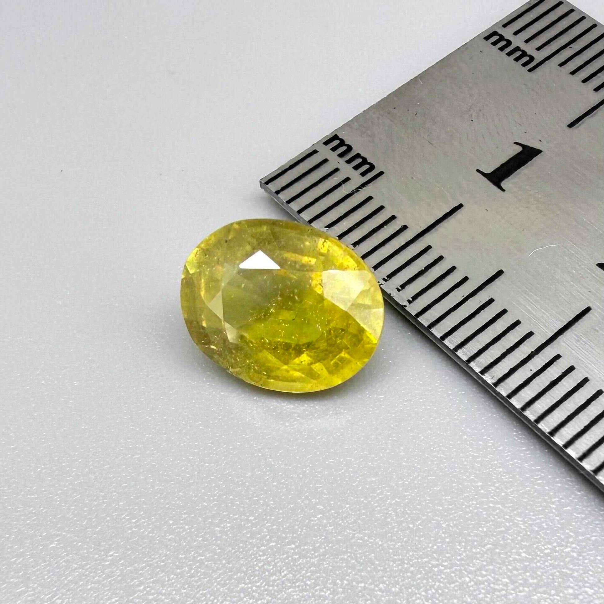 Oval yellow sapphire from Africa, 5.42ct, with vivid golden-yellow color, visible natural inclusions and a transparent to slightly silky appearance.