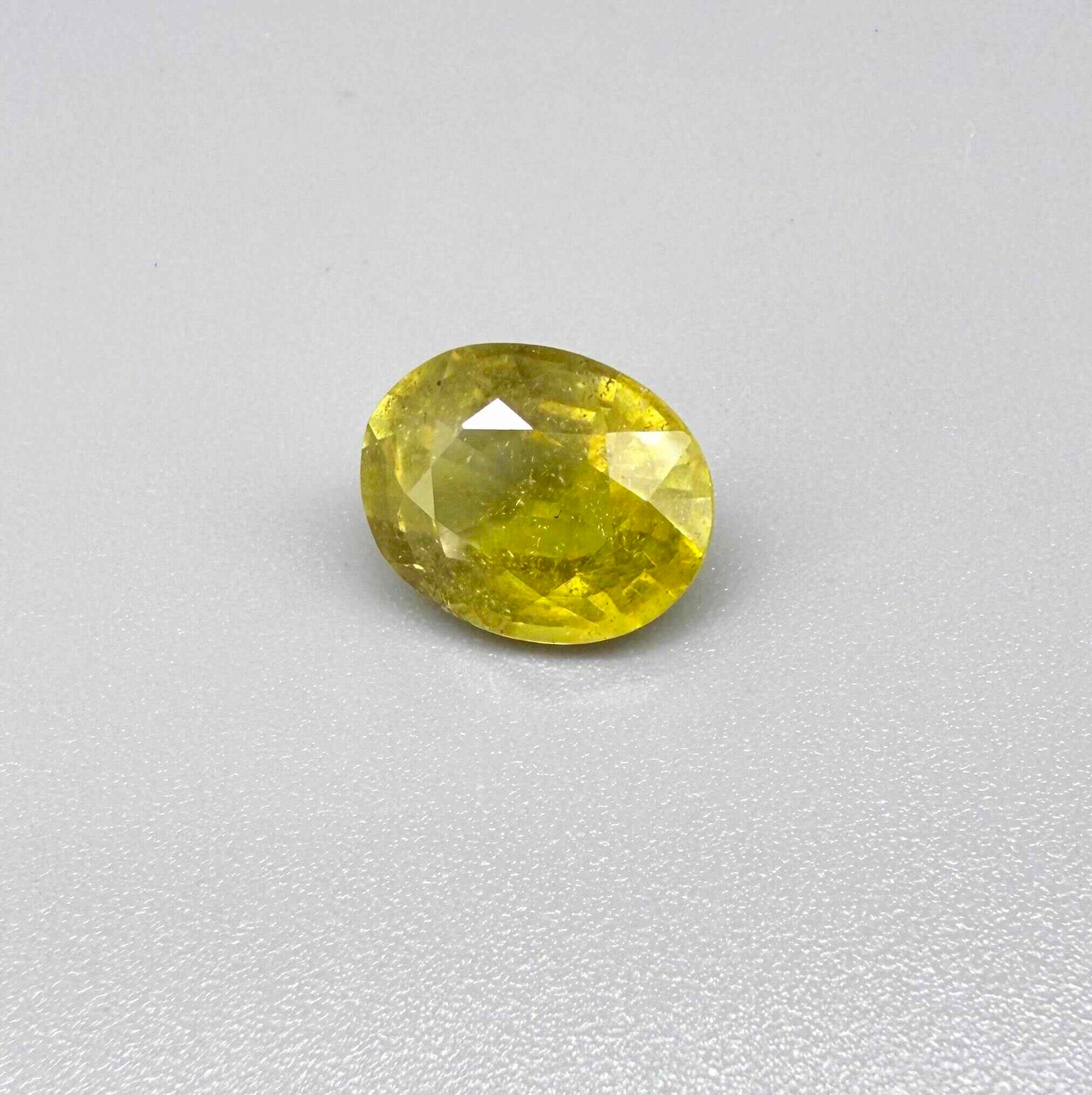 Oval yellow sapphire from Africa, 5.42ct, with vivid golden-yellow color, visible natural inclusions and a transparent to slightly silky appearance.