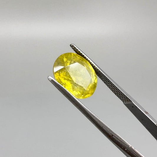 Oval yellow sapphire from Africa, 5.42ct, with vivid golden-yellow color, visible natural inclusions and a transparent to slightly silky appearance.