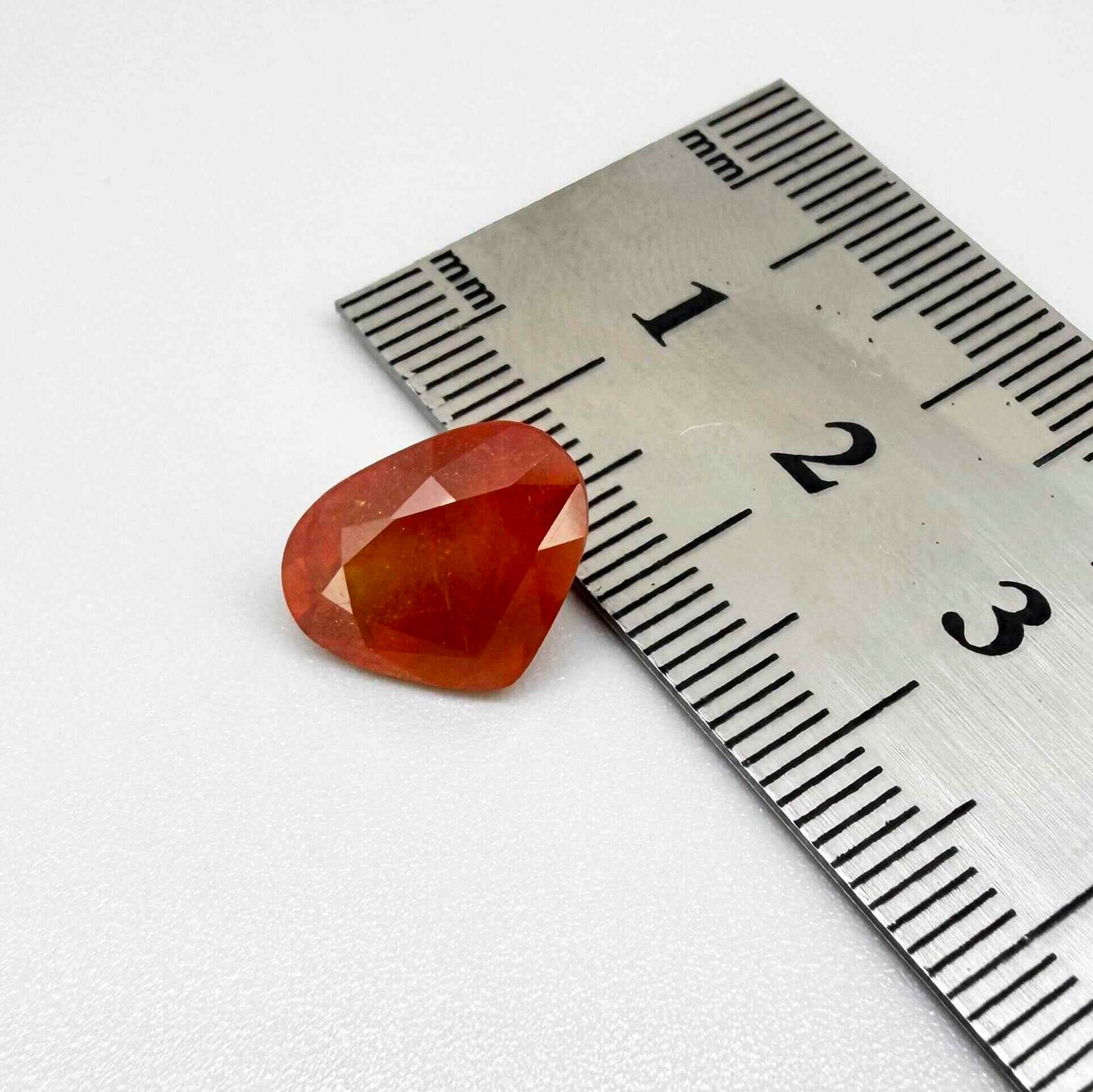 Heart cut orange sapphire from Africa, 6.76ct, with vivid orange to reddish-orange color, visible natural inclusions and a transparent to slightly silky appearance.