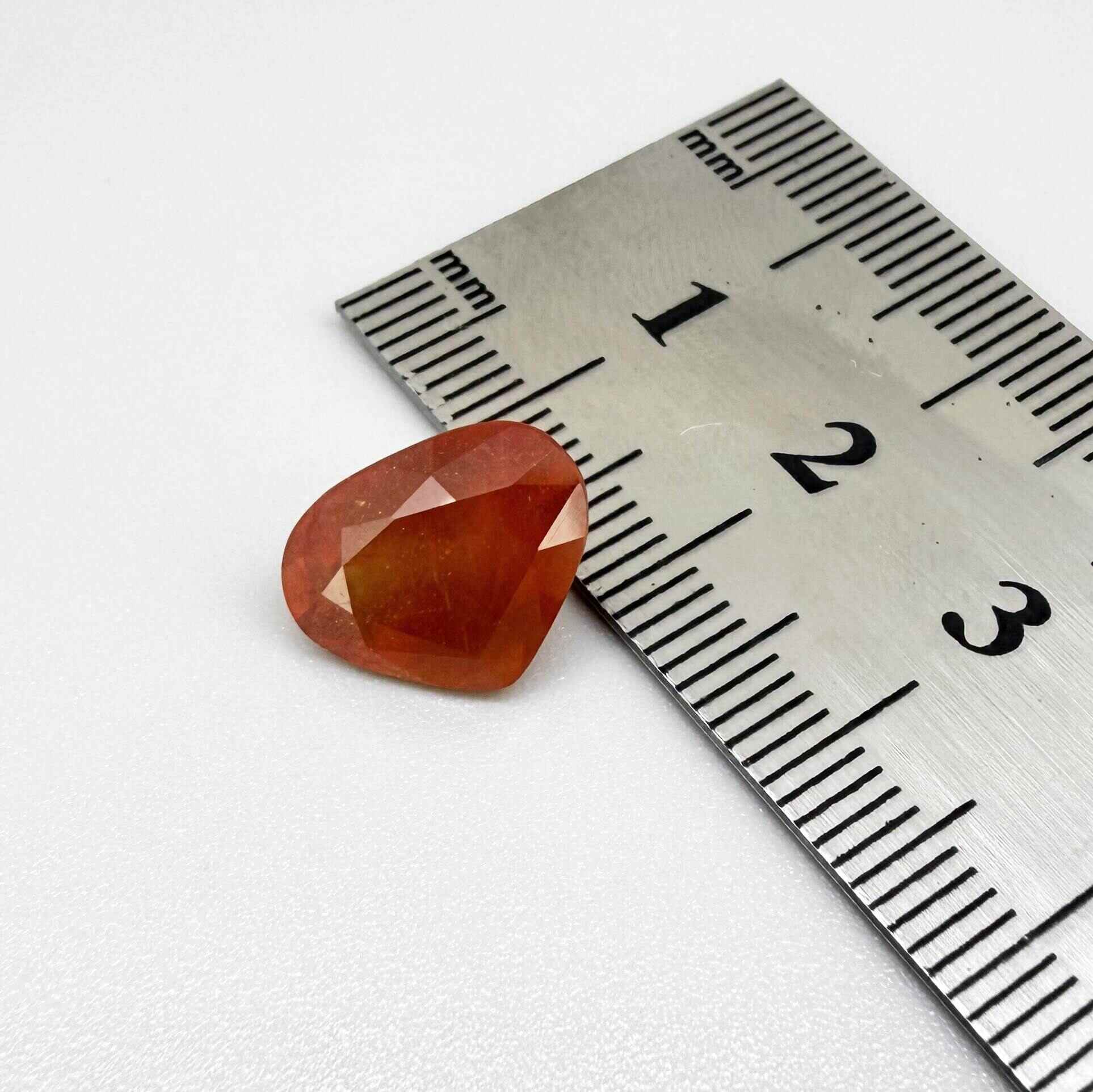 Heart cut orange sapphire from Africa, 6.76ct, with vivid orange to reddish-orange color, visible natural inclusions and a transparent to slightly silky appearance.