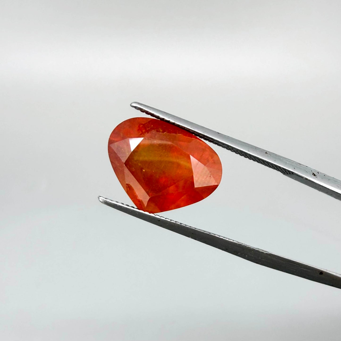 Heart cut orange sapphire from Africa, 6.76ct, with vivid orange to reddish-orange color, visible natural inclusions and a transparent to slightly silky appearance.
